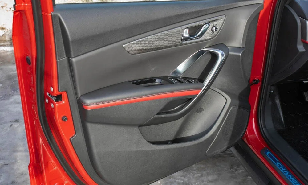 Фото Changan CS55 — дверная карта, фото 2. Внутренняя панель двери: сочетание материалов и компоновка управления в красно-чёрной гамме. Решётка динамика в двери — часть штатной акустики Changan CS55 — дверная карта, фото 2