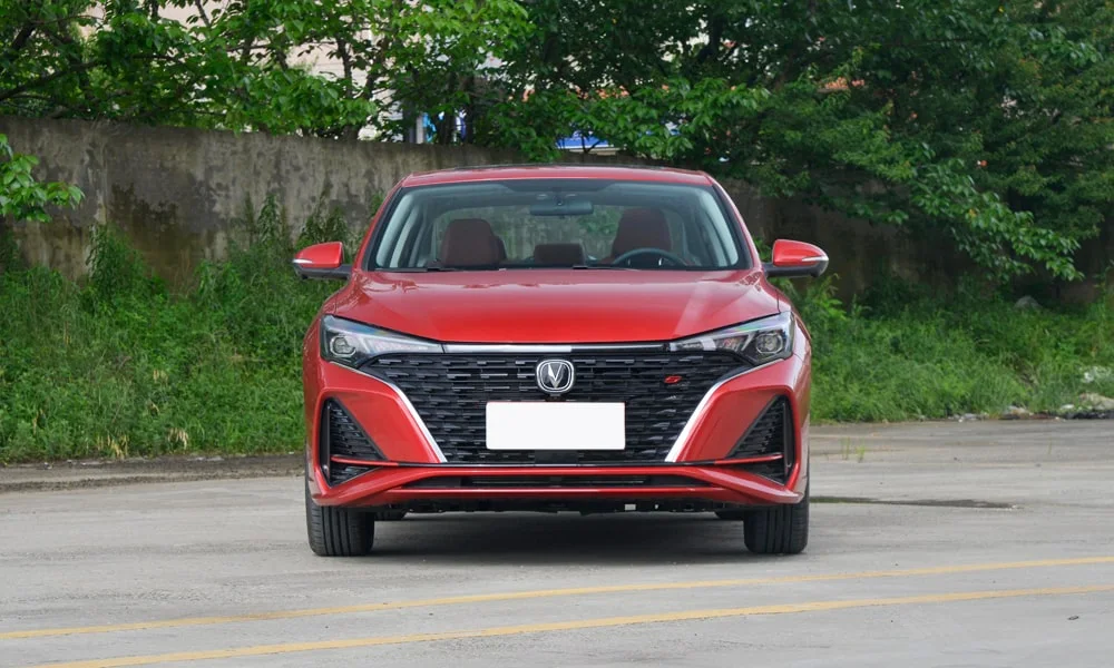 Фото Changan Eado (2024) — вид спереди, фото 5. Кузов в красном цвете: рисунок оптики и решётки задаёт узнаваемое «лицо» модели. Дневные ходовые огни включаются автоматически с запуском Changan Eado (2024) — вид спереди, фото 5