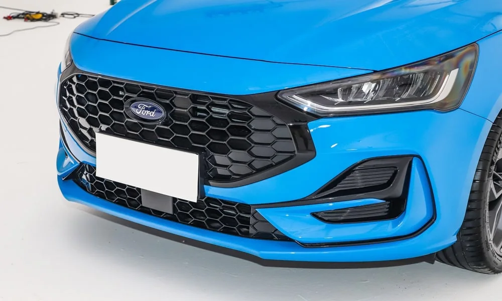 Фото Ford Focus (2024) — решётка радиатора. Рисунок решётки: сетка, ламели или глухая панель у электроверсий. За решёткой у многих комплектаций стоит радар адаптивного круиз-контроля Ford Focus (2024) — решётка радиатора