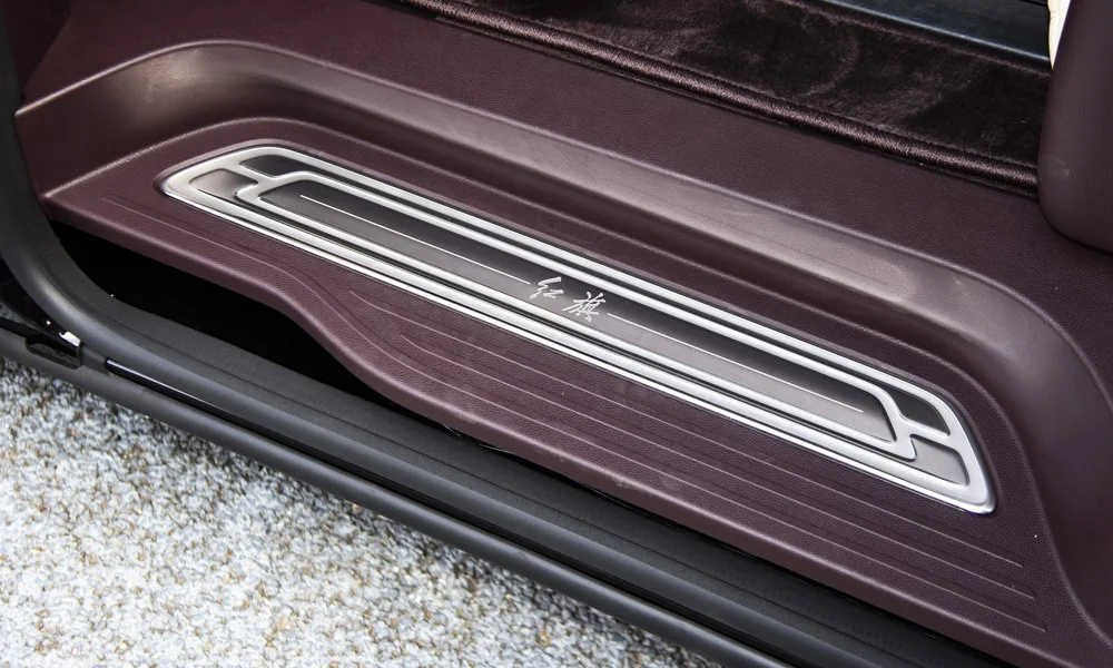 Фото Hongqi HQ9 (2023) — дверная карта. Дверная карта в коричневой отделке: подлокотник, динамик и блок стеклоподъёмников. Решётка динамика в двери — часть штатной акустики Hongqi HQ9 (2023) — дверная карта