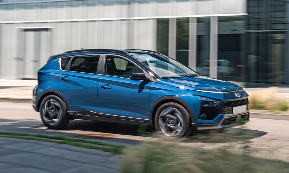 Фото Hyundai Bayon (2024) — вид спереди, фото 4. Синий кузов, строгая симметрия оптики — базовый ракурс знакомства с дизайном. Рисунок ходовых огней — подпись модели, по нему её узнают в потоке Hyundai Bayon (2024) — вид спереди, фото 4