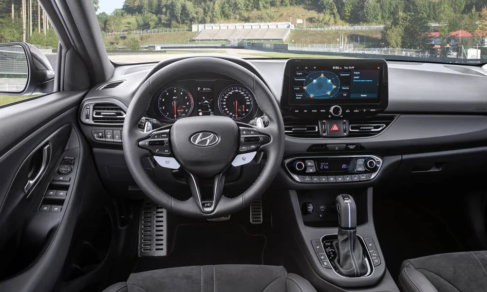 Фото Hyundai i30 Fastback N (2024) — передняя панель. Архитектура передней панели: ярусы, вставки и консоль в тёмной гамме. Минимум физических кнопок — ставка на экранное управление Hyundai i30 Fastback N (2024) — передняя панель