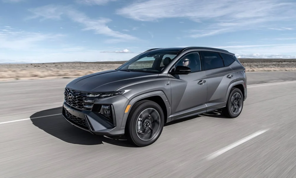 Фото Hyundai Tucson N Line (2024) — вид спереди, фото 7. Кузов в сером цвете: рисунок оптики и решётки задаёт узнаваемое «лицо» модели. Рисунок ходовых огней — подпись модели, по нему её узнают в потоке Hyundai Tucson N Line (2024) — вид спереди, фото 7
