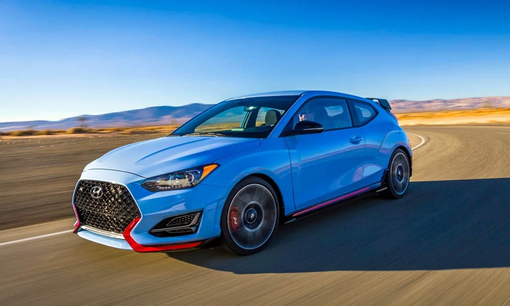 Фото Hyundai Veloster N (2024) — вид спереди, фото 9. Синий кузов, строгая симметрия оптики — базовый ракурс знакомства с дизайном. Дневные ходовые огни включаются автоматически с запуском Hyundai Veloster N (2024) — вид спереди, фото 9