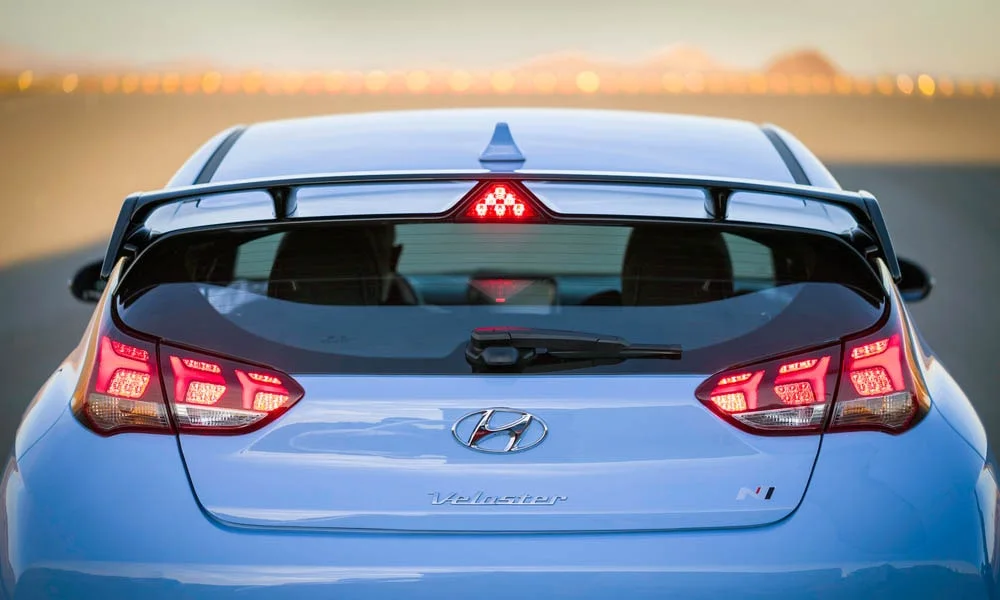 Фото Hyundai Veloster N (2024) — вид сзади, фото 8. Линия крыши, стойки и задняя дверь в синем исполнении. Насадки выхлопа или их имитация внизу бампера различают версии Hyundai Veloster N (2024) — вид сзади, фото 8