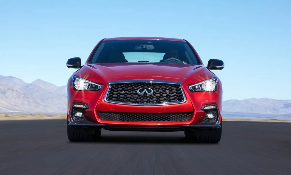 Фото Infiniti Q50 — вид спереди, фото 8. Красный кузов, строгая симметрия оптики — базовый ракурс знакомства с дизайном. Рисунок ходовых огней — подпись модели, по нему её узнают в потоке Infiniti Q50 — вид спереди, фото 8