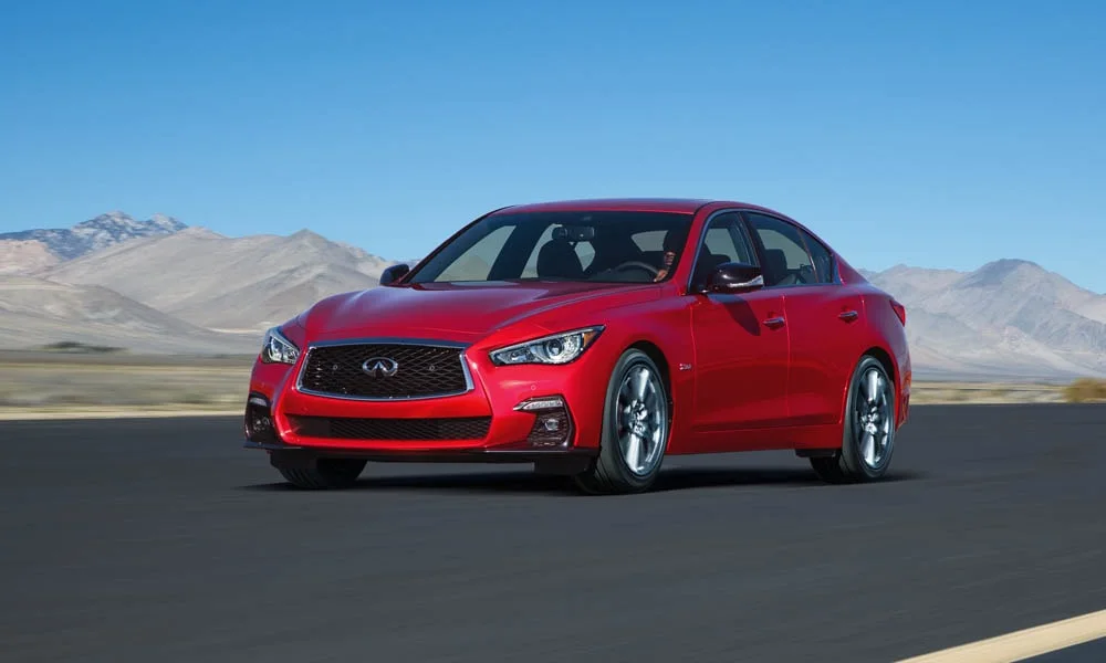 Фото Infiniti Q50 — вид спереди, фото 13. Красный кузов, строгая симметрия оптики — базовый ракурс знакомства с дизайном. Рисунок ходовых огней — подпись модели, по нему её узнают в потоке Infiniti Q50 — вид спереди, фото 13