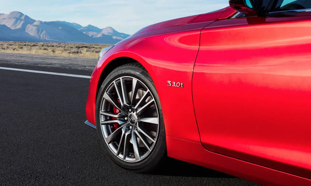 Фото Infiniti Q50 — вид сбоку, фото 3. Сбоку читаются линия остекления и характер выштамповок на красном кузове. Хромированные или чёрные молдинги окон отличают комплектации Infiniti Q50 — вид сбоку, фото 3