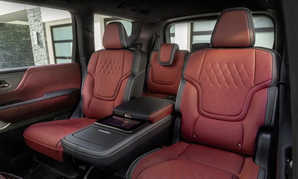 Фото Infiniti QX80 (2024) — задние сиденья. Посадка второго ряда: подголовники и подлокотник. Плоский пол упрощает посадку втроём Infiniti QX80 (2024) — задние сиденья