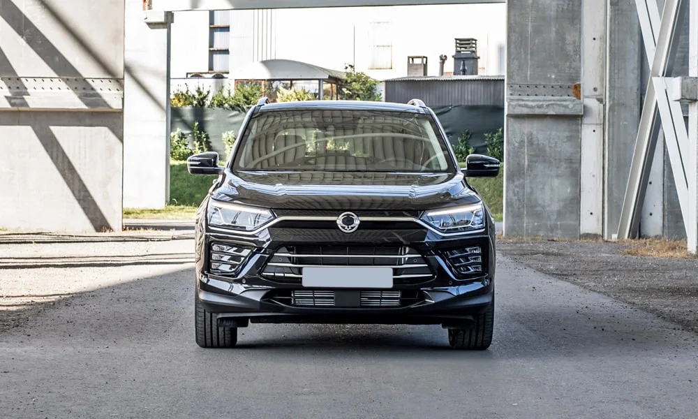 Фото KGM Korando (2024) — вид спереди, фото 4. Передок в чёрном исполнении — крупная светотехника и выразительный бампер. Рисунок ходовых огней — подпись модели, по нему её узнают в потоке KGM Korando (2024) — вид спереди, фото 4