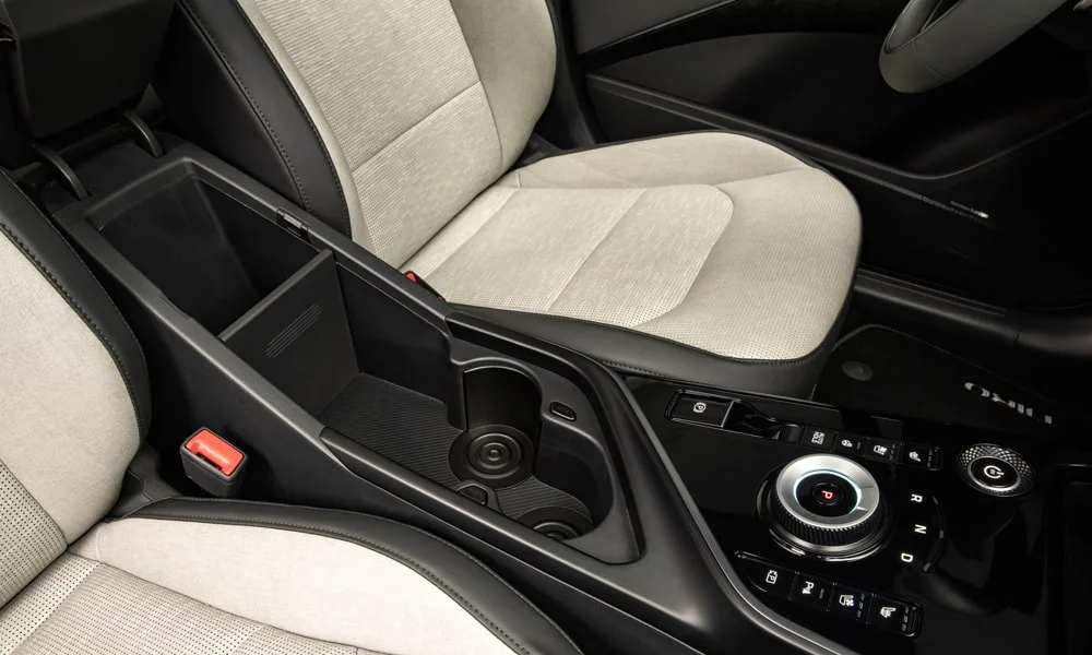 Фото KIA Niro — центральная консоль. Бокс консоли открыт: организация хранения между креслами. Прорезиненное дно ниш удерживает мелочи в поворотах KIA Niro — центральная консоль