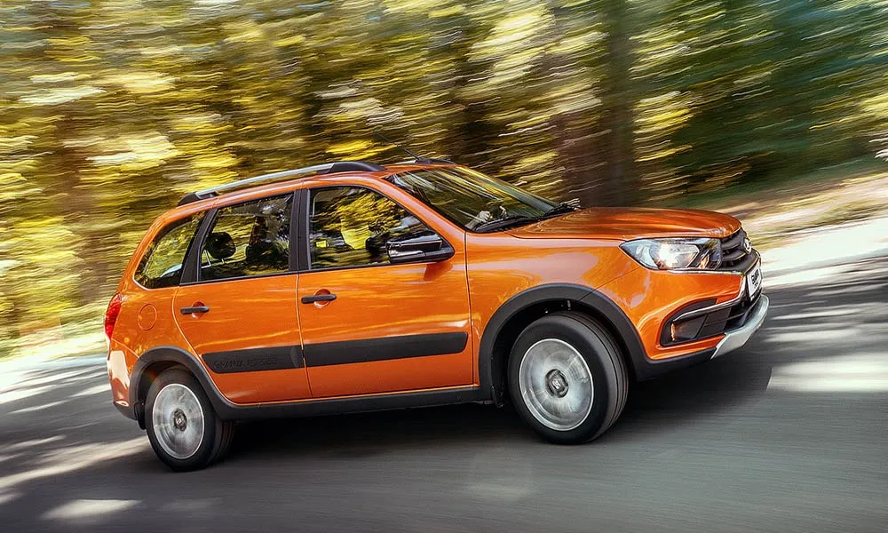 Фото LADA Granta Cross — вид сбоку, фото 2. Сбоку читаются линия остекления и характер выштамповок на оранжевом кузове LADA Granta Cross — вид сбоку, фото 2