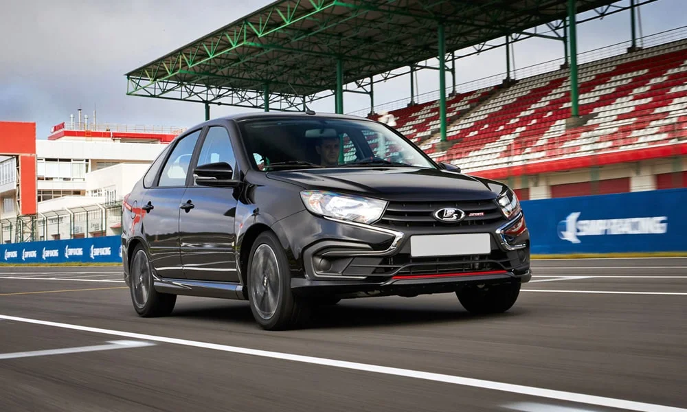 Фото LADA Granta Sport Лифтбек (2023) — вид спереди, фото 9. Чёрный кузов, строгая симметрия оптики — базовый ракурс знакомства с дизайном. Дневные ходовые огни включаются автоматически с запуском LADA Granta Sport Лифтбек (2023) — вид спереди, фото 9