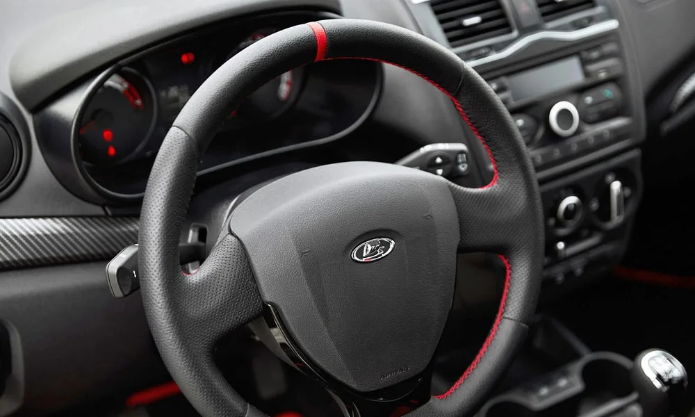 Фото LADA Granta Sport Лифтбек (2023) — руль, фото 2. Обшивка обода и компоновка спиц крупным планом. Правильная посадка: руки на «9 и 3», приборы читаются поверх обода LADA Granta Sport Лифтбек (2023) — руль, фото 2