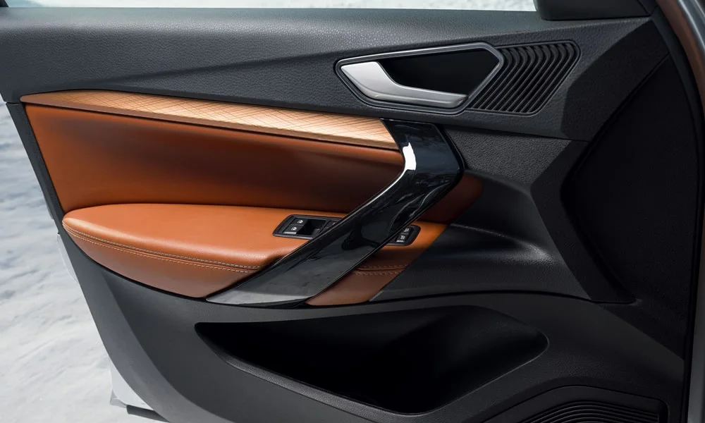 Фото LADA Vesta Cross (2023) — дверная карта. Внутренняя панель двери: сочетание материалов и компоновка управления в коричневой гамме. Решётка динамика в двери — часть штатной акустики LADA Vesta Cross (2023) — дверная карта