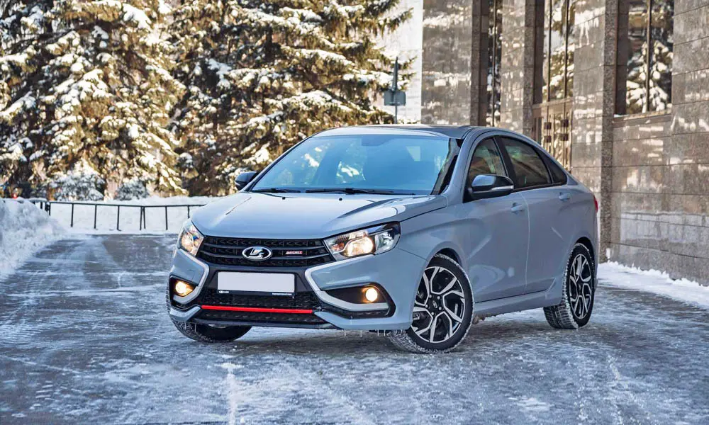 Фото LADA Vesta Sport (2026) — вид спереди, фото 3. Серый кузов, строгая симметрия оптики — базовый ракурс знакомства с дизайном. Рисунок ходовых огней — подпись модели, по нему её узнают в потоке LADA Vesta Sport (2026) — вид спереди, фото 3