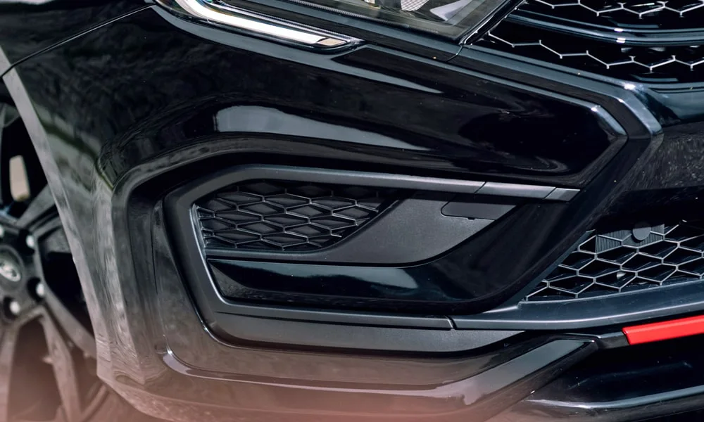 Фото LADA Vesta Sportline (2023) — решётка радиатора. Фирменный рисунок облицовки — визитная карточка марки. Активные жалюзи за решёткой закрываются на трассе ради аэродинамики — есть у ряда моделей LADA Vesta Sportline (2023) — решётка радиатора