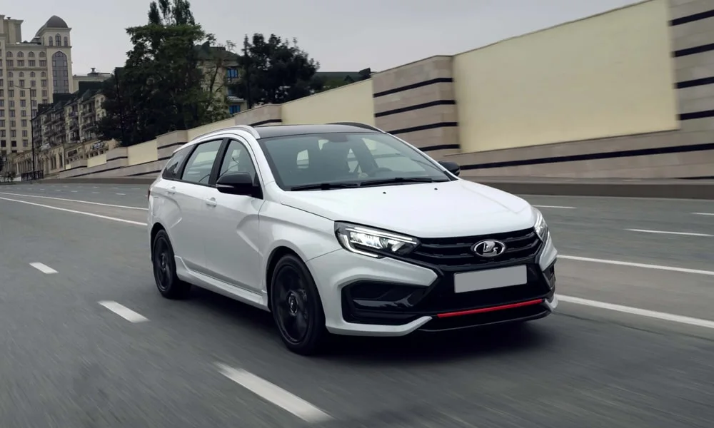 Фото LADA Vesta SW Sportline — вид спереди, фото 9. Кузов в белом цвете: рисунок оптики и решётки задаёт узнаваемое «лицо» модели. Рисунок ходовых огней — подпись модели, по нему её узнают в потоке LADA Vesta SW Sportline — вид спереди, фото 9
