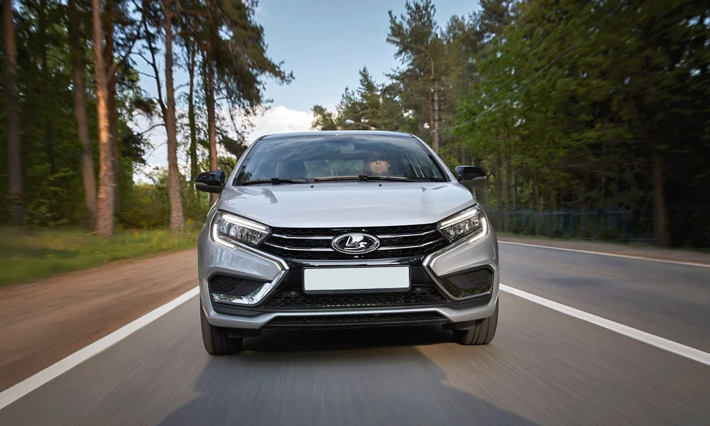 Фото LADA Vesta (2023) — вид спереди, фото 7. Кузов в серебристом цвете: рисунок оптики и решётки задаёт узнаваемое «лицо» модели. Дневные ходовые огни включаются автоматически с запуском LADA Vesta (2023) — вид спереди, фото 7