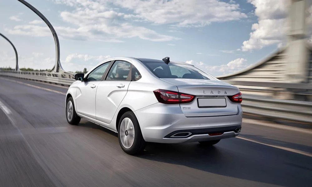 Фото LADA Vesta (2023) — вид сзади, фото 7. Серебристый кузов сзади — фонари и бампер определяют ночной образ модели. Насадки выхлопа или их имитация внизу бампера различают версии LADA Vesta (2023) — вид сзади, фото 7