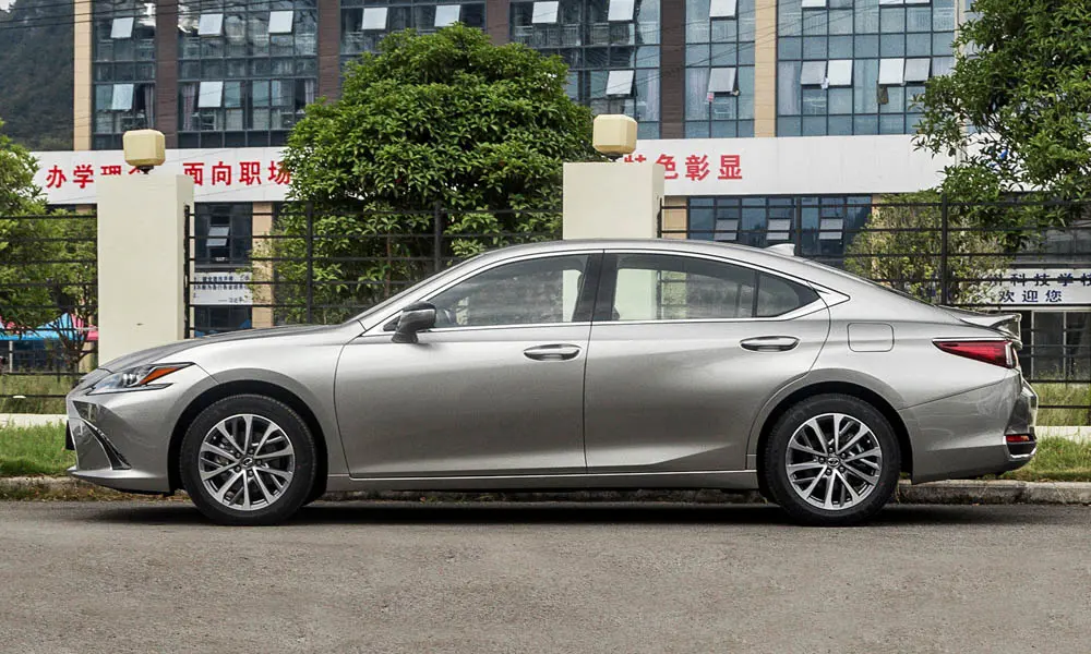 Фото Lexus ES 200 — вид сбоку, фото 2. Профиль кузова: колёсная база, свесы и линия остекления. Хромированные или чёрные молдинги окон отличают комплектации Lexus ES 200 — вид сбоку, фото 2