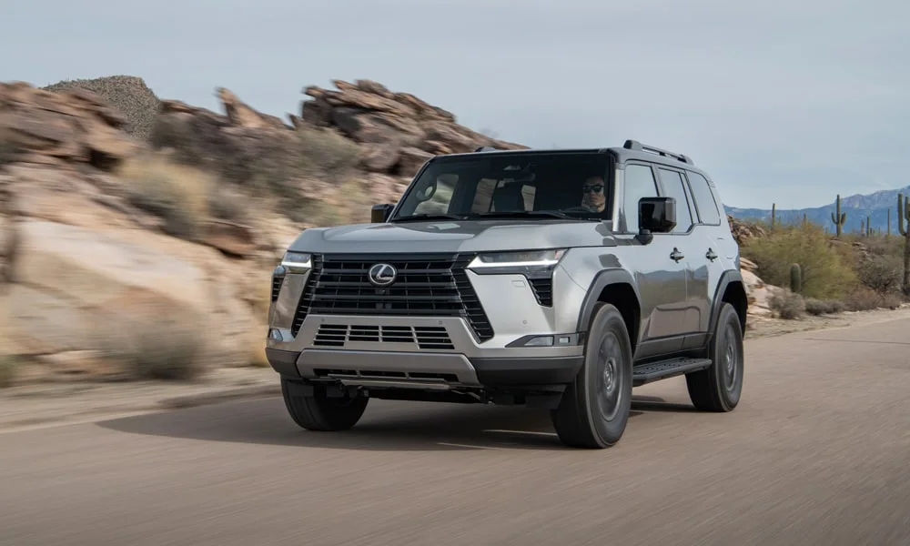Фото Lexus GX 550 (2024) — вид спереди, фото 4. Серый кузов, строгая симметрия оптики — базовый ракурс знакомства с дизайном. Дневные ходовые огни включаются автоматически с запуском Lexus GX 550 (2024) — вид спереди, фото 4