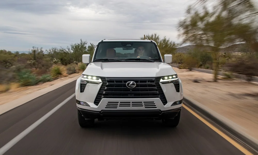 Фото Lexus GX 550 (2024) — вид спереди, фото 8. Передок в белом исполнении — крупная светотехника и выразительный бампер. Дневные ходовые огни включаются автоматически с запуском Lexus GX 550 (2024) — вид спереди, фото 8
