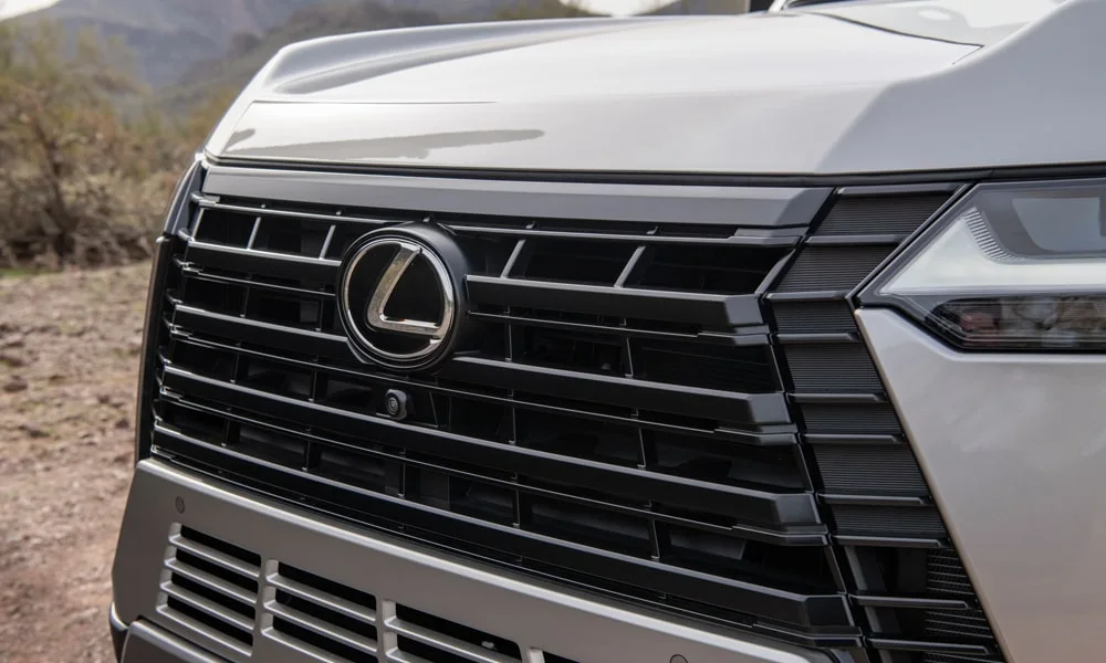 Фото Lexus GX 550 (2024) — решётка радиатора. Фирменный рисунок облицовки — визитная карточка марки. Активные жалюзи за решёткой закрываются на трассе ради аэродинамики — есть у ряда моделей Lexus GX 550 (2024) — решётка радиатора