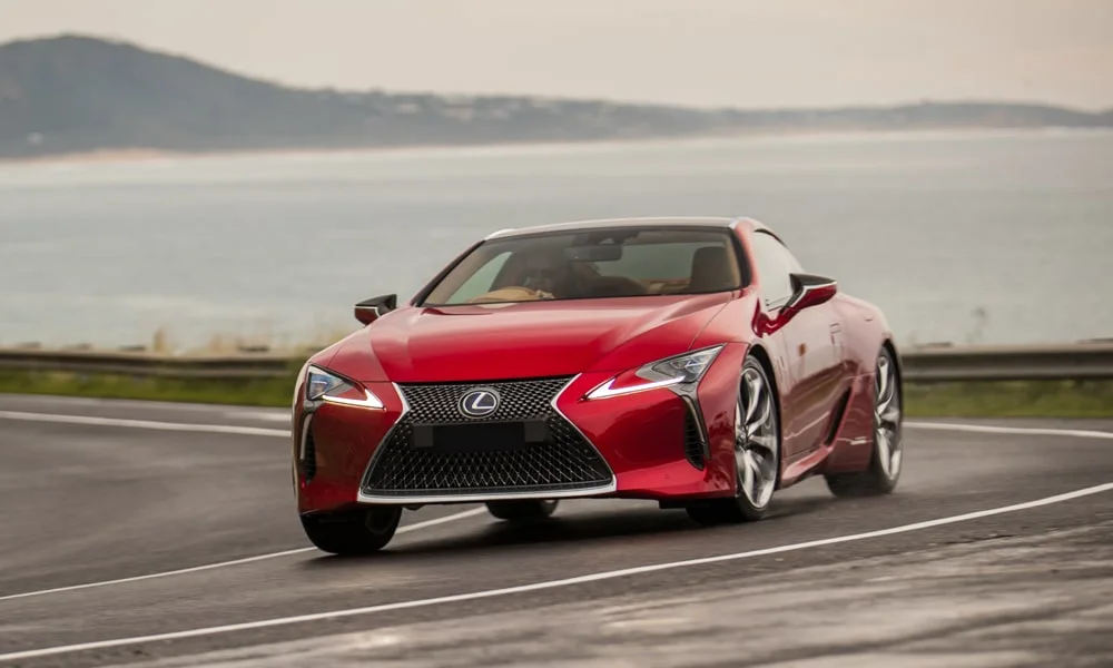 Фото Lexus LC 500 — вид спереди, фото 5. Красный кузов, строгая симметрия оптики — базовый ракурс знакомства с дизайном. Дневные ходовые огни включаются автоматически с запуском Lexus LC 500 — вид спереди, фото 5