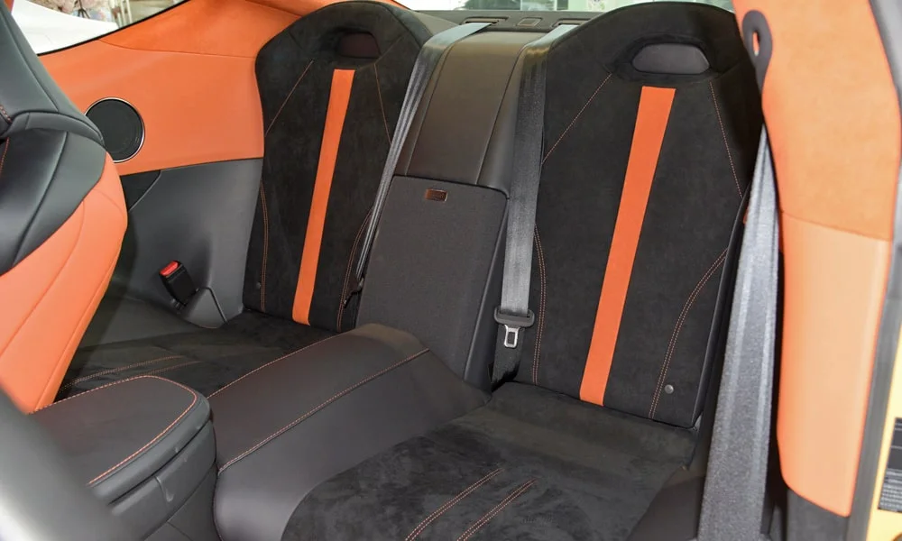 Фото Lexus LC 500 — задние сиденья. Посадка второго ряда: подголовники и подлокотник. Плоский пол упрощает посадку втроём Lexus LC 500 — задние сиденья
