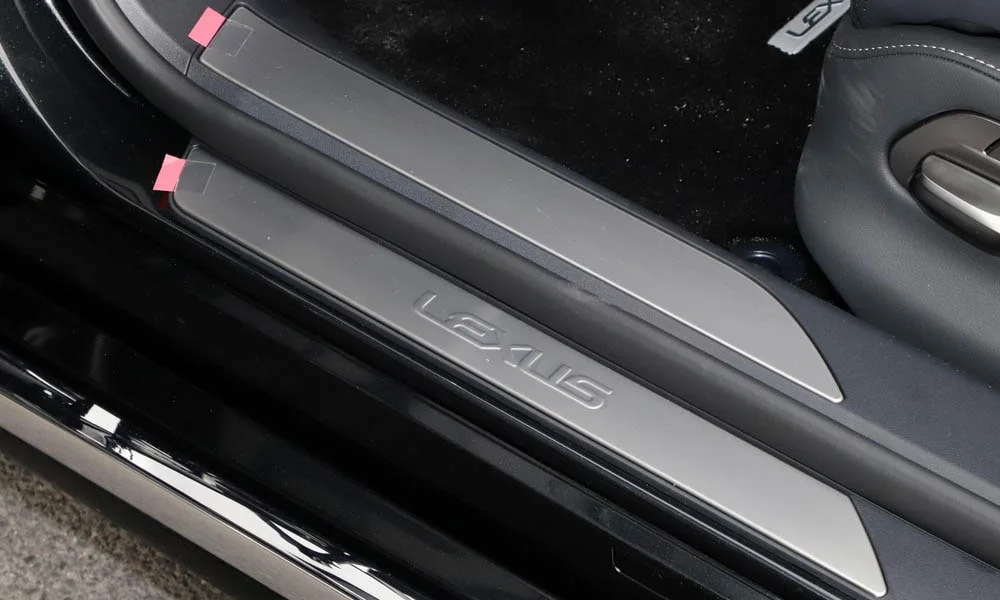 Фото Lexus LS 500 — дверная карта. Дверная карта в тёмной отделке: подлокотник, динамик и блок стеклоподъёмников. Решётка динамика в двери — часть штатной акустики Lexus LS 500 — дверная карта
