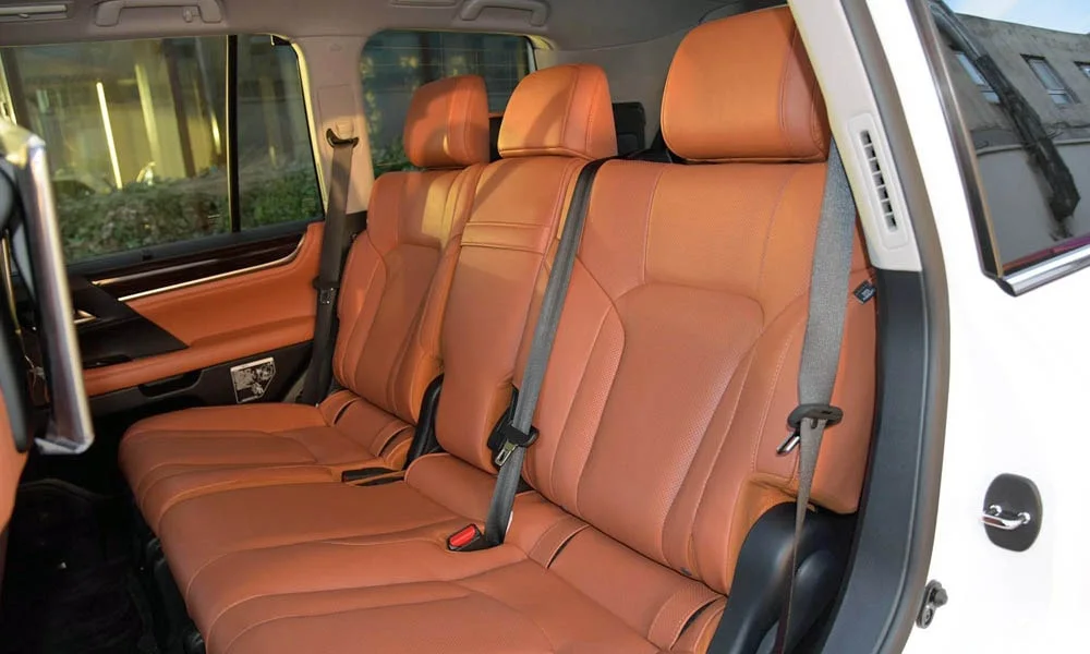 Фото Lexus LX 450d — задние сиденья. Задний диван в гладкой коже: посадка и центральный подлокотник Lexus LX 450d — задние сиденья