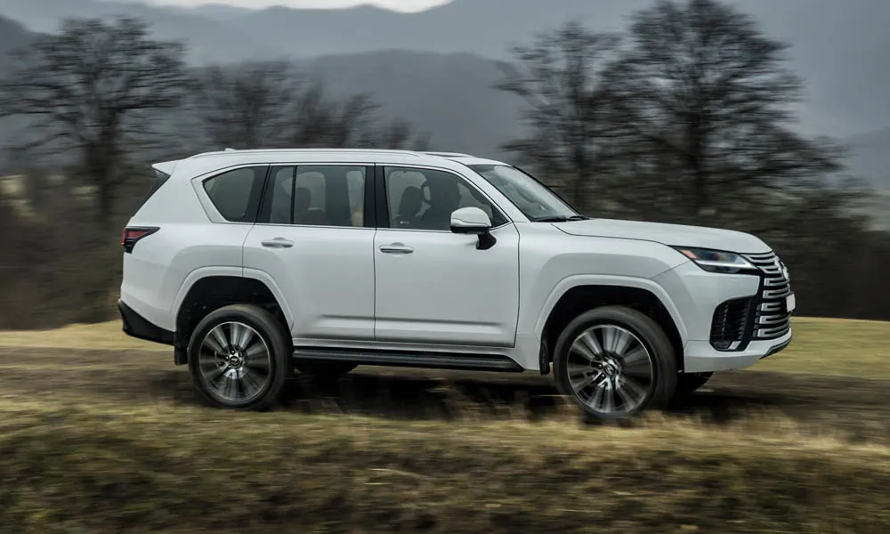 Фото Lexus LX 500d (2022) — вид спереди, фото 7. Белый кузов, строгая симметрия оптики — базовый ракурс знакомства с дизайном. Рисунок ходовых огней — подпись модели, по нему её узнают в потоке Lexus LX 500d (2022) — вид спереди, фото 7