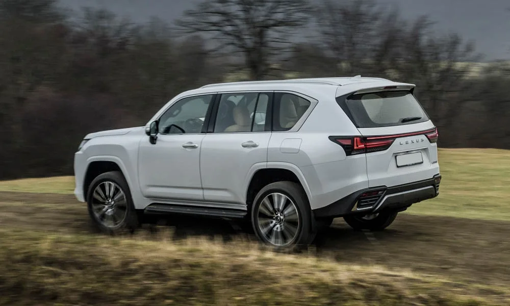 Фото Lexus LX 500d (2022) — вид сзади, фото 8. Корма в белом цвете: графика фонарей и пластика пятой двери. Светодиодная полоса или раздельные секции — задняя оптика стала главным украшением кормы Lexus LX 500d (2022) — вид сзади, фото 8