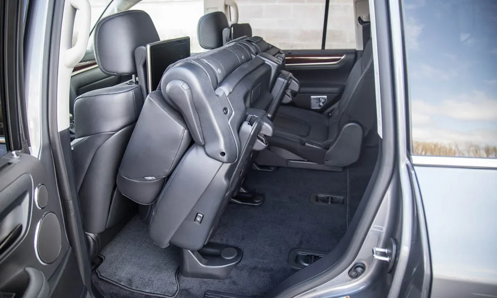 Фото Lexus LX 570 — задние сиденья. Задний диван в гладкой коже: посадка и центральный подлокотник. Плоский пол упрощает посадку втроём Lexus LX 570 — задние сиденья