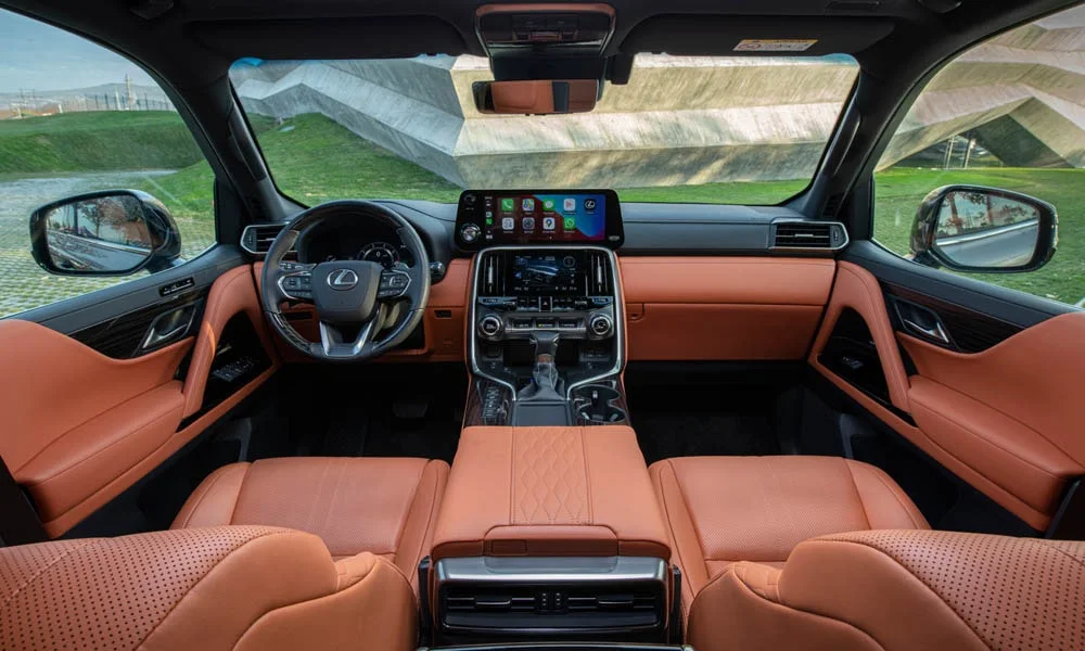Фото Lexus LX 600 (2022) — передняя панель. Панель в коричневой отделке — видна компоновка экранов и органов управления. Мягкие материалы верхнего яруса и вставки задают уровень интерьера Lexus LX 600 (2022) — передняя панель