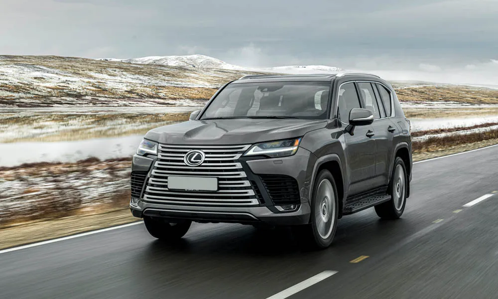 Фото Lexus LX 600 (2022) — вид спереди, фото 9. Передок в сером исполнении — крупная светотехника и выразительный бампер Lexus LX 600 (2022) — вид спереди, фото 9