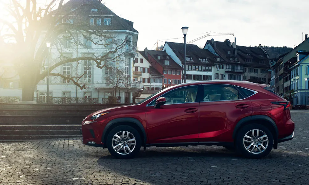 Фото Lexus NX 200 — вид сбоку. Сбоку читаются линия остекления и характер выштамповок на красном кузове Lexus NX 200 — вид сбоку