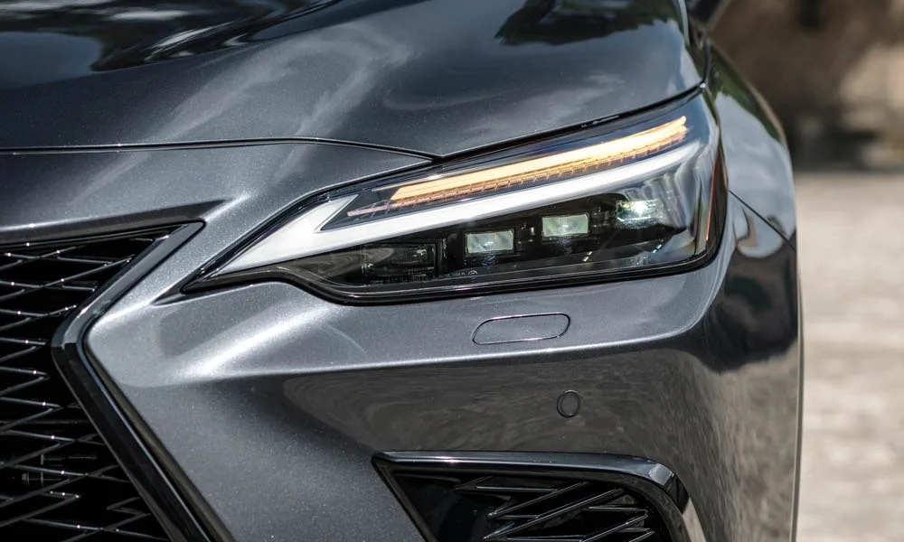 Фото Lexus NX 450h (2024) — вид спереди, фото 4. Кузов в сером цвете: рисунок оптики и решётки задаёт узнаваемое «лицо» модели Lexus NX 450h (2024) — вид спереди, фото 4