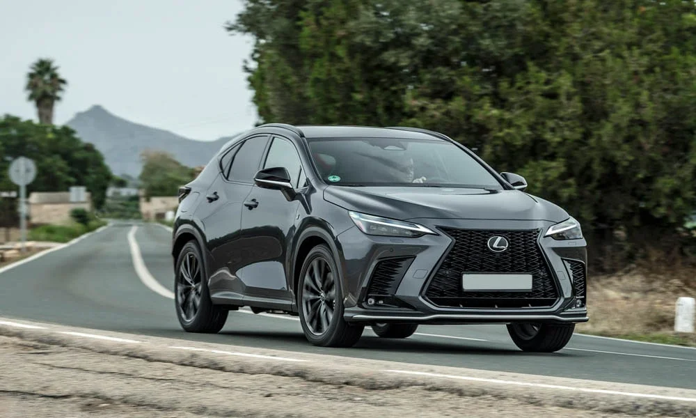 Фото Lexus NX 450h (2024) — вид спереди, фото 6. Чёрный кузов, строгая симметрия оптики — базовый ракурс знакомства с дизайном. Рисунок ходовых огней — подпись модели, по нему её узнают в потоке Lexus NX 450h (2024) — вид спереди, фото 6