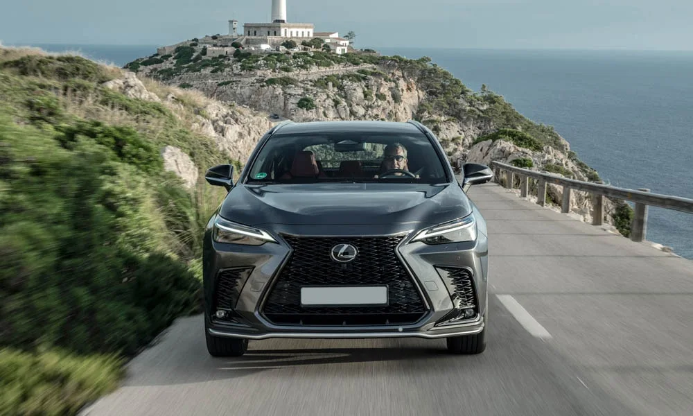 Фото Lexus NX 450h (2024) — вид спереди, фото 8. Кузов в сером цвете: рисунок оптики и решётки задаёт узнаваемое «лицо» модели Lexus NX 450h (2024) — вид спереди, фото 8