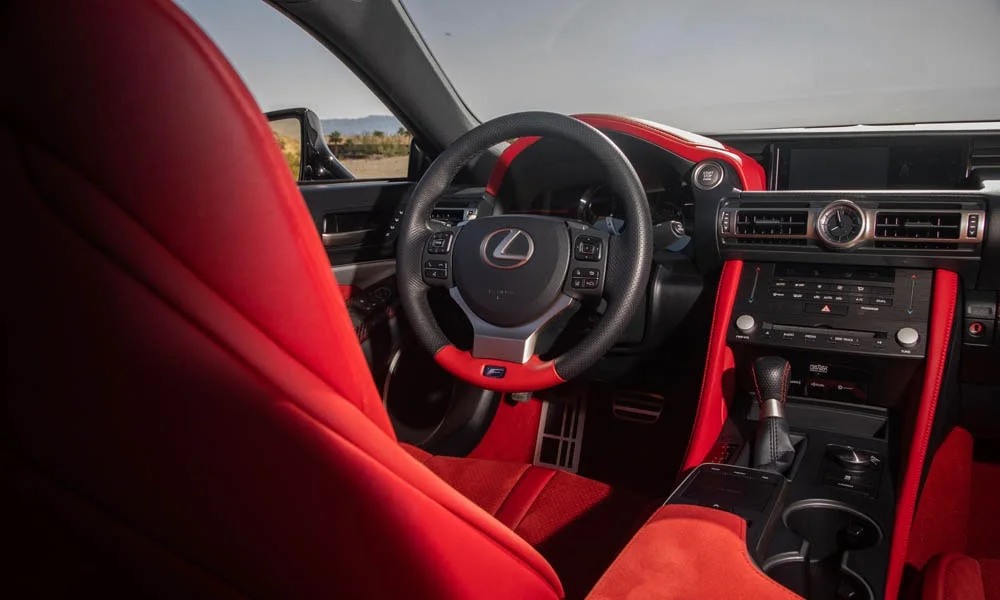 Фото Lexus RC F (2024) — руль. Обшивка обода и компоновка спиц крупным планом. Клавиши на спицах управляют медиа, круизом и ассистентами — руки остаются на руле Lexus RC F (2024) — руль