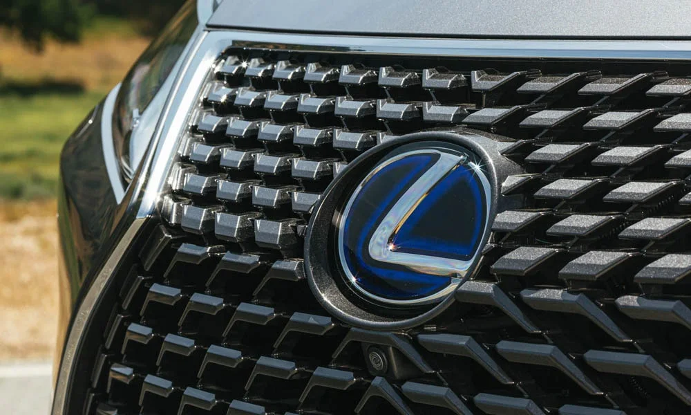 Фото Lexus RX 350L — решётка радиатора. Фирменный рисунок облицовки — визитная карточка марки. Активные жалюзи за решёткой закрываются на трассе ради аэродинамики — есть у ряда моделей Lexus RX 350L — решётка радиатора