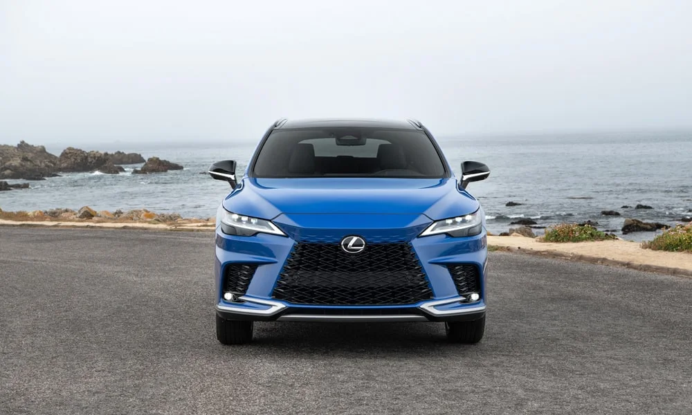 Фото Lexus RX 350 (2024) — вид спереди, фото 3. Синий кузов, строгая симметрия оптики — базовый ракурс знакомства с дизайном. Дневные ходовые огни включаются автоматически с запуском Lexus RX 350 (2024) — вид спереди, фото 3