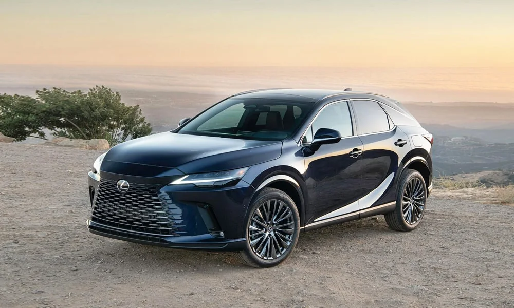 Фото Lexus RX 350h (2024) — вид спереди, фото 7. Синий кузов, строгая симметрия оптики — базовый ракурс знакомства с дизайном. Рисунок ходовых огней — подпись модели, по нему её узнают в потоке Lexus RX 350h (2024) — вид спереди, фото 7