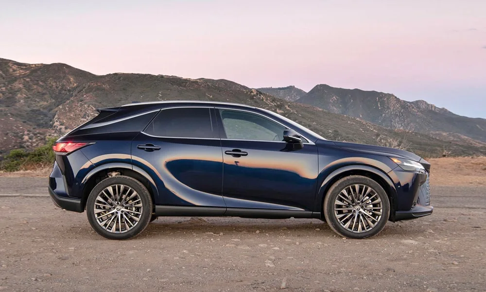 Фото Lexus RX 350h (2024) — вид сбоку, фото 2. Сбоку читаются линия остекления и характер выштамповок на синем кузове. Длинная база — простор второго ряда; короткие свесы упрощают парковку Lexus RX 350h (2024) — вид сбоку, фото 2