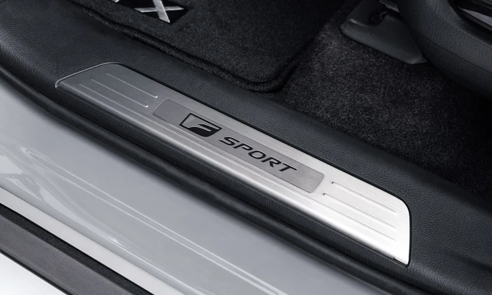 Фото Lexus TX 500h — дверная карта. Дверная карта в светло-серой отделке: подлокотник, динамик и блок стеклоподъёмников. Решётка динамика в двери — часть штатной акустики Lexus TX 500h — дверная карта