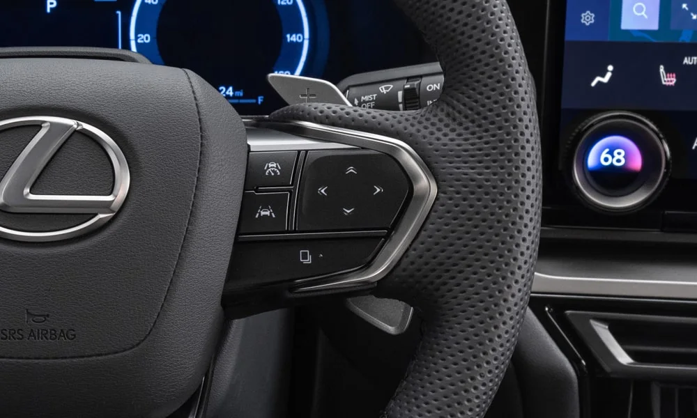 Фото Lexus TX 500h — руль, фото 3. Обшивка обода и компоновка спиц крупным планом. Клавиши на спицах управляют медиа, круизом и ассистентами — руки остаются на руле Lexus TX 500h — руль, фото 3