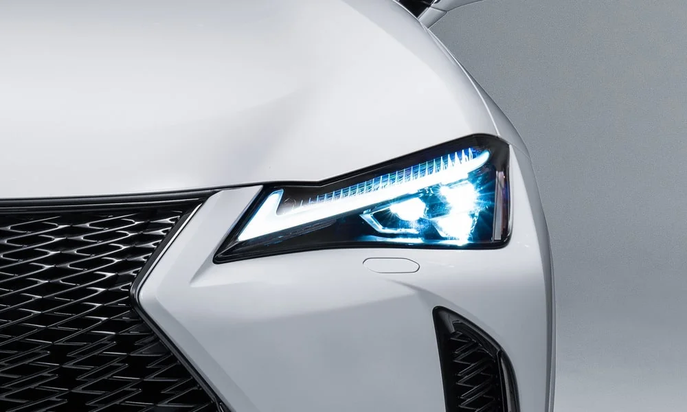 Фото Lexus UX 200 (2024) — передняя оптика. Линзы и секции ходовых огней крупным планом. Автоматический дальний свет сам переключается при встречном разъезде — есть у ряда версий Lexus UX 200 (2024) — передняя оптика