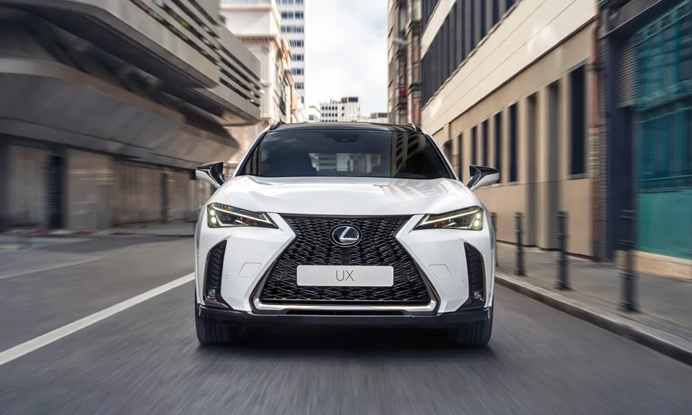 Фото Lexus UX 250h (2024) — вид спереди, фото 3. Анфас: пропорции капота, посадка кузова и графика ходовых огней. Рисунок ходовых огней — подпись модели, по нему её узнают в потоке Lexus UX 250h (2024) — вид спереди, фото 3